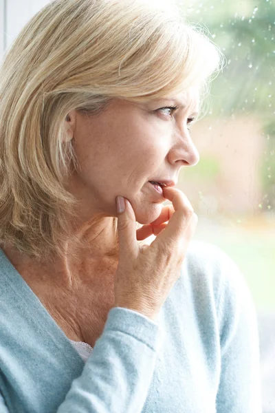 Triste mature femme souffrant de agoraphobie regardant hors de Windo — Photo