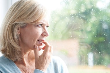 Sad Mature Woman Suffering From Agoraphobia Looking Out Of Windo clipart