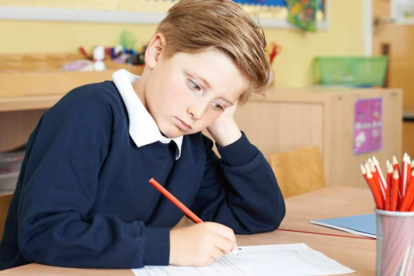 Aburrido alumno de la escuela primaria masculina en el escritorio —  Fotos de Stock