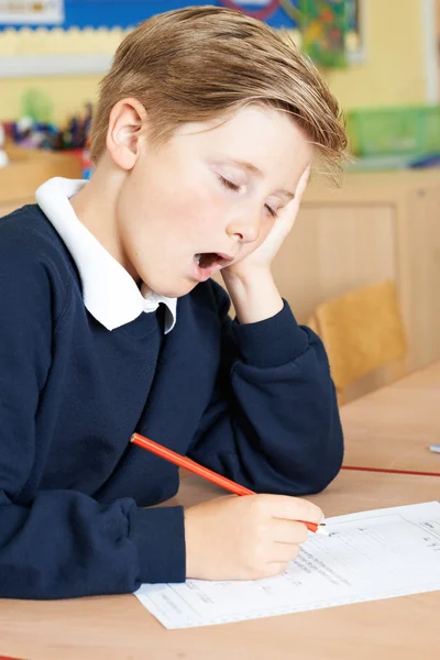 Aluno da escola primária masculina bocejando na sala de aula — Fotografia de Stock