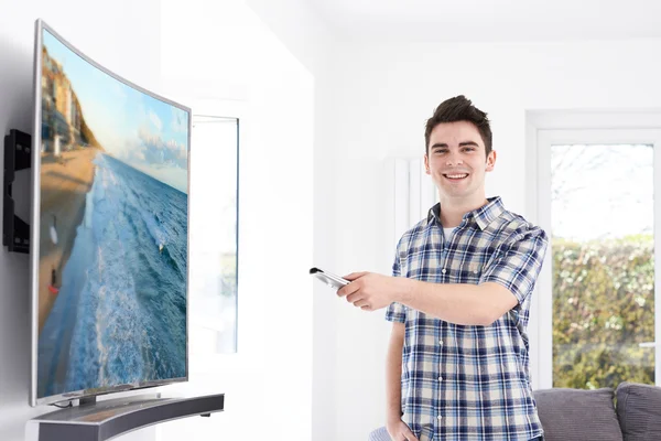Genç adam evde yeni kavisli ekran televizyonlu