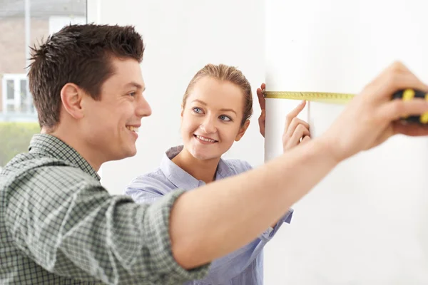 Junges Paar misst Mauer im neuen Zuhause — Stockfoto