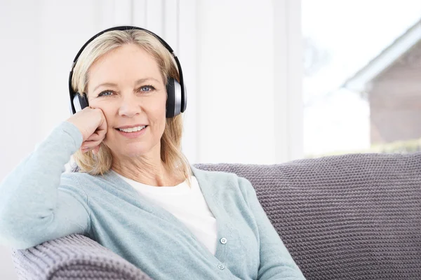 Mogen kvinna lyssna på musik på trådlösa hörlurar — Stockfoto