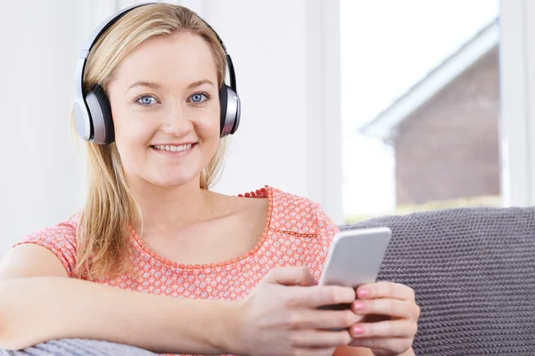 Mulher transmite música do telefone móvel para fones de ouvido sem fio — Fotografia de Stock