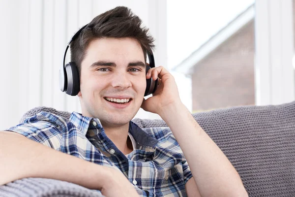 Jovem ouvindo música em fones de ouvido sem fio — Fotografia de Stock