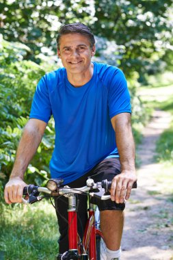 Olgun adam kırsalında yol boyunca Bisiklete binme