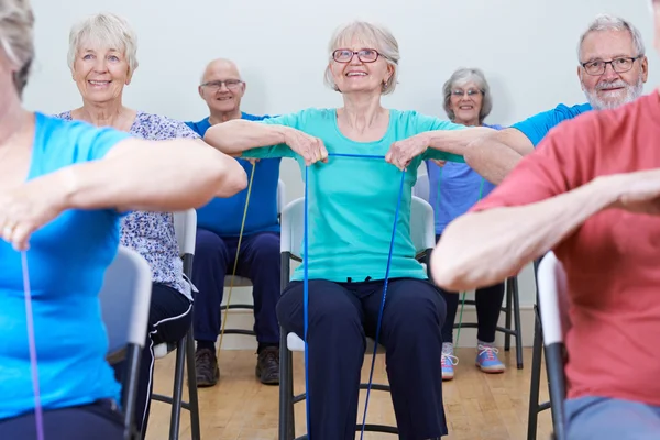 Grupo de personas mayores usando bandas de resistencia en la clase de fitness —  Fotos de Stock