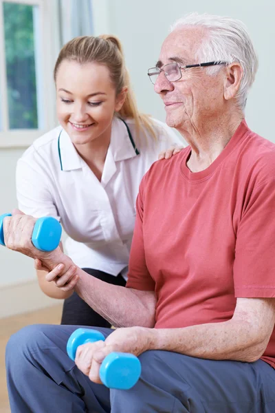 Hombre mayor trabajando con fisioterapeuta usando pesas — Foto de Stock