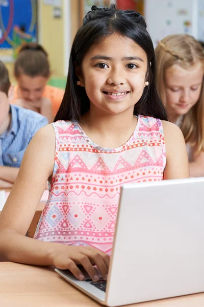 Alumna de la escuela primaria femenina usando el ordenador portátil en la clase de informática —  Fotos de Stock