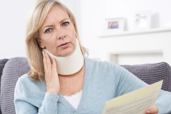 Reife Frau liest Brief nach Nackenverletzung — Stockfoto