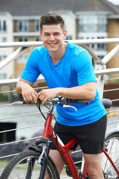 Young Man Cycling Next To River In Urban Setting — Stock Photo, Image