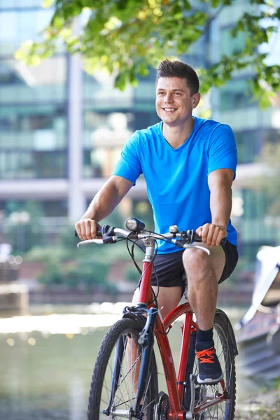 都会の川の横にある自転車の若い男 — ストック写真