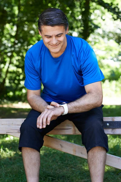 Mature Man Looking At Activity Tracker Whilst Exercising In Coun — Stock Photo, Image