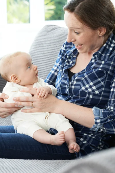 Madre coccole bambino figlia su divano — Foto Stock