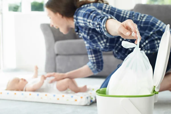 Madre desechando pañales de bebé en la papelera — Foto de Stock