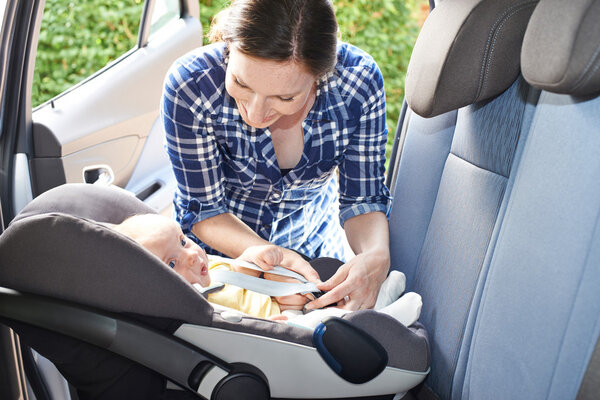 Mother Putting Baby into to Car Seat for Journey
