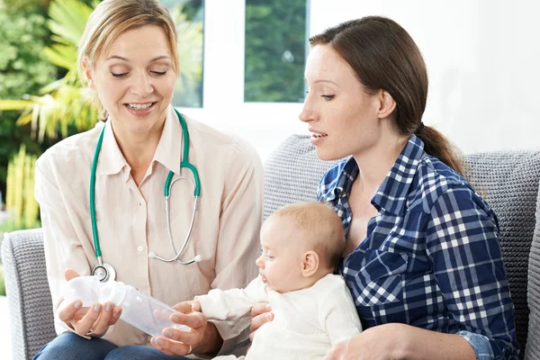 Health Visitor Giving Mother Advice On Feeding Baby With Bottle Royalty Free Stock Images