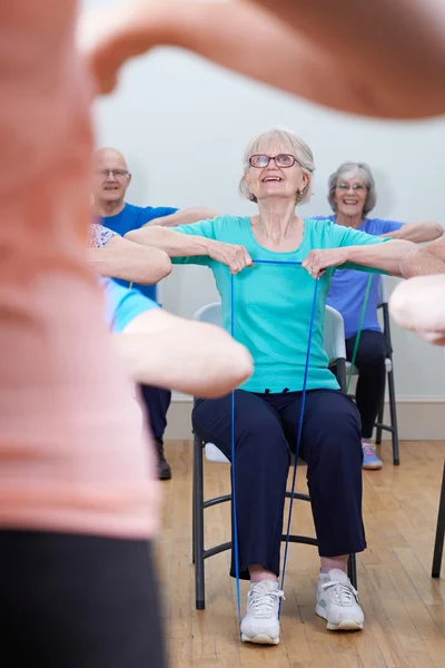 Grupo de personas mayores usando bandas de resistencia en la clase de fitness — Foto de Stock