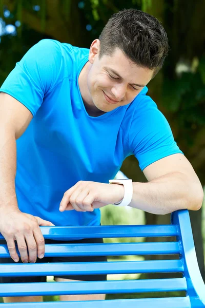 Man Looking At Activity Tracker Whilst Exercising In Park — Stock Photo, Image