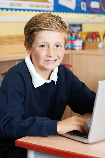 Alumno de la escuela primaria masculina usando el ordenador portátil en la clase de computadora — Foto de Stock