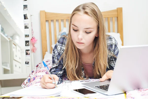 Adolescente chica usando el ordenador portátil para hacer la tarea en el dormitorio — Foto de Stock