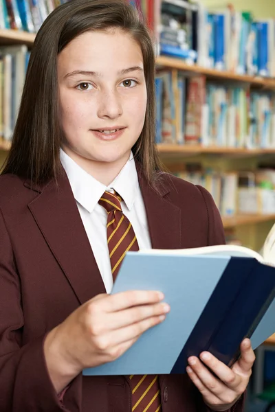 Meisje School Uniform leesboek dragen In bibliotheek — Stockfoto