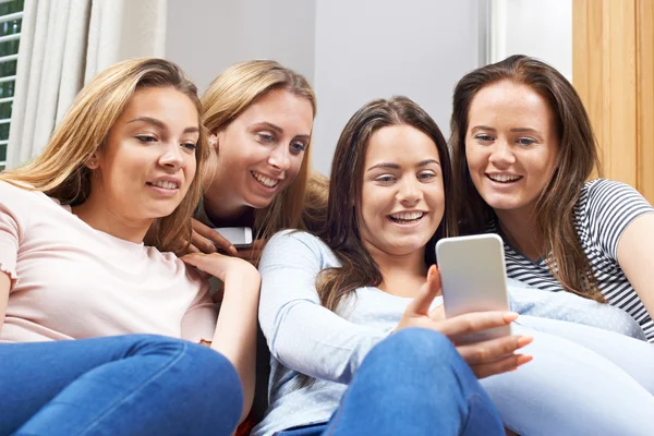 Группа девочек-подростков, читающих текстовые сообщения на мобильном телефоне — стоковое фото