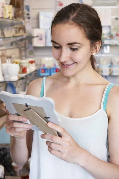 Kvinnliga shopper tittar på bildramen i butik — Stockfoto