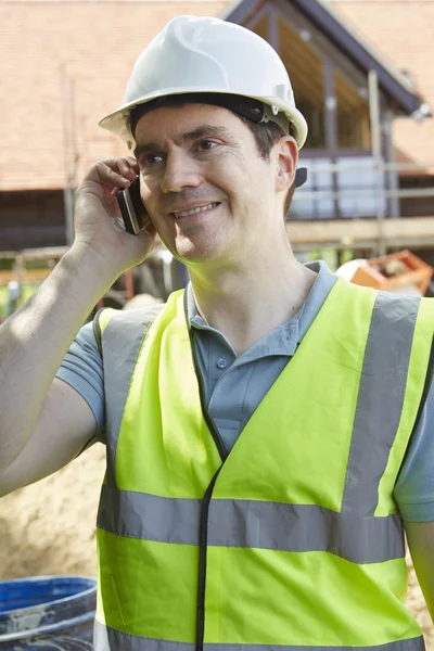 Byggnadsarbetare på byggnadsplatsen med mobiltelefon — Stockfoto