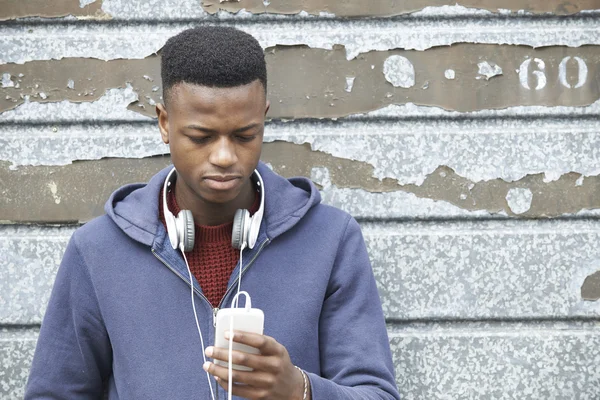 Tizenéves fiú, fárasztó fejhallgató és városi s zenét hallgat — Stock Fotó