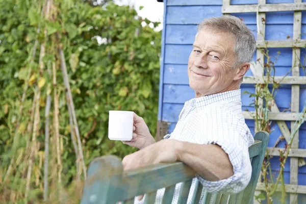 Starší muž relaxační v zahradě s šálkem kávy — Stock fotografie