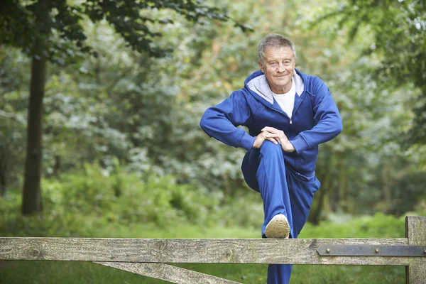 Hombre mayor estirándose en carrera de campo — Foto de Stock