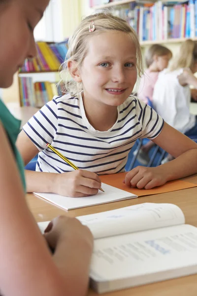 Grundskolan eleven arbetar på skrivbord i klassrummet — Stockfoto