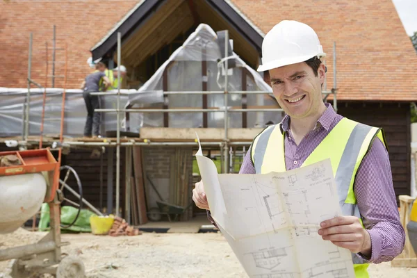 Arquitecto en el sitio del edificio mirando los planes de la casa — Foto de Stock