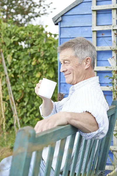 Starší muž relaxační v zahradě s šálkem kávy — Stock fotografie