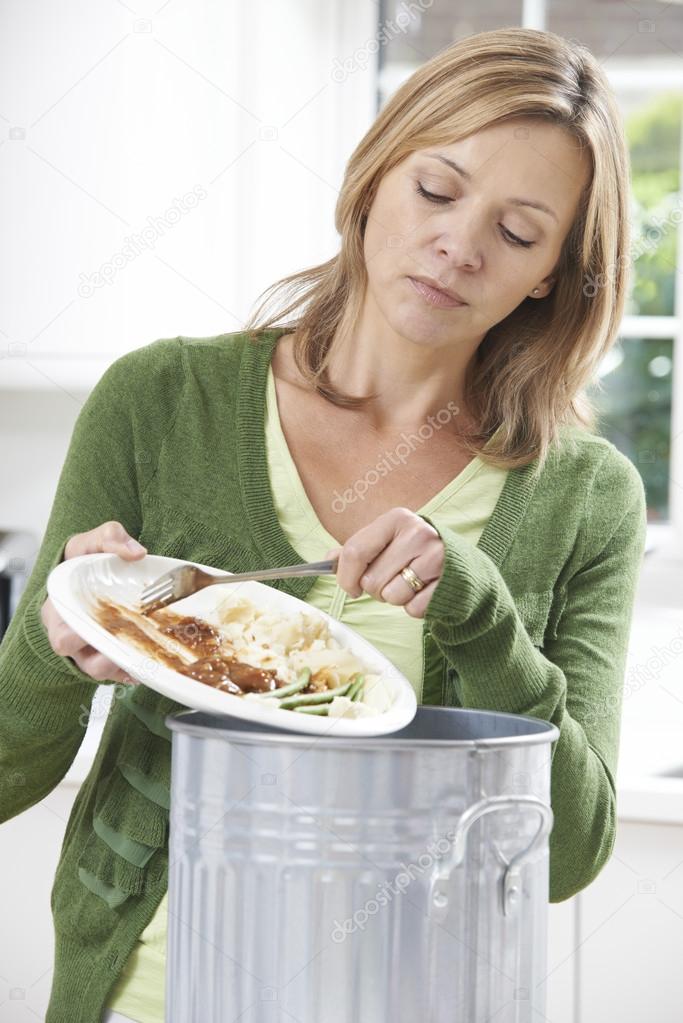 Woman Scraping Food Leftovers Into Garbage Bin