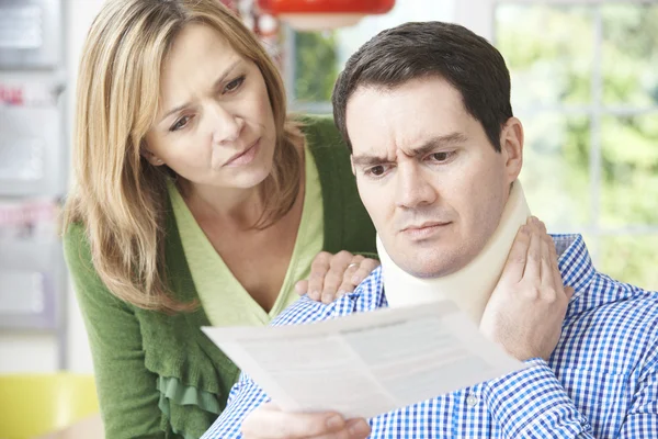 Couple Reading Letter In Respect Of Husband's Neck Injury — Stock Photo, Image