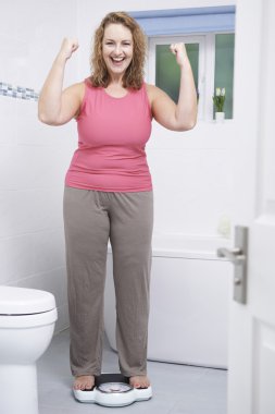 Mutlu kadın kendini ölçeklerde banyoda Tartım