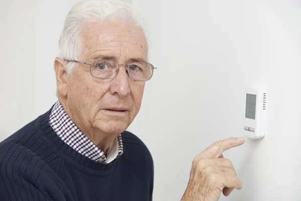 Bezorgd Senior Man draaien van centrale verwarming thermostaat — Stockfoto