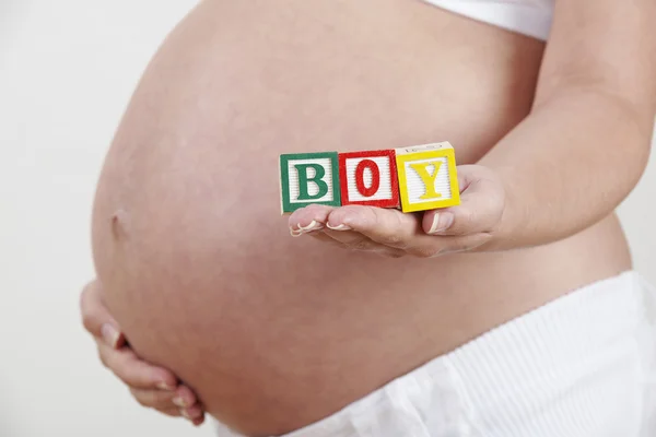 Gravid kvinna med trä blockerar stavning pojke — Stockfoto