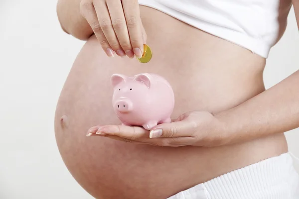 Close up van de zwangere vrouw die munt in spaarpot — Stockfoto