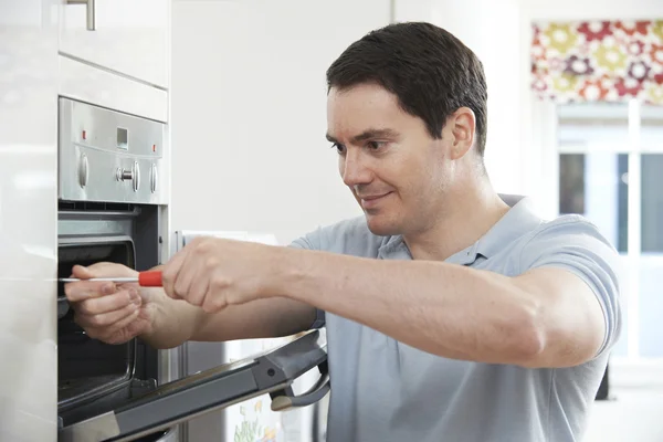 Reparador que fixa o forno doméstico na cozinha — Fotografia de Stock