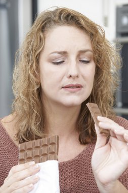 Guilty Woman On Diet Eating Chocolate Bar At Home clipart