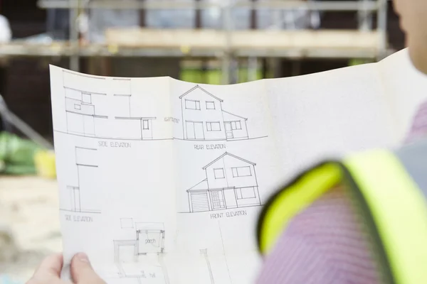 Arquitecto en el sitio del edificio mirando los planes para la casa — Foto de Stock