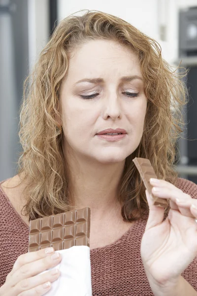 Mulher culpada na dieta comer chocolate bar em casa — Fotografia de Stock