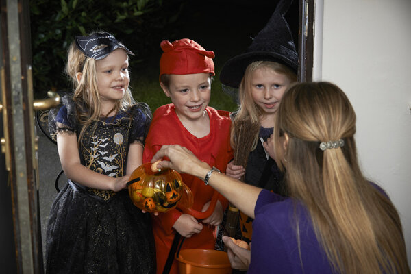 Halloween Party With Children Trick Or Treating In Costume
