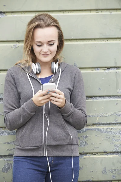 Tonårsflicka bär hörlurar och lyssna på musik i urban — Stockfoto