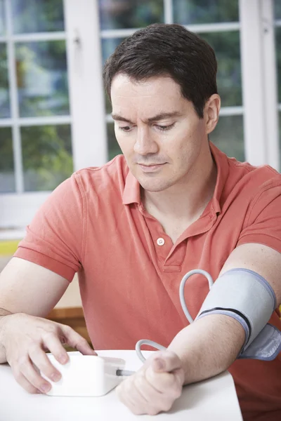 Muž, měření krevního tlaku doma — Stock fotografie