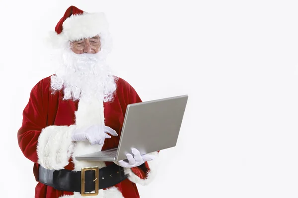 Santa Claus usando el ordenador portátil en el fondo blanco — Foto de Stock