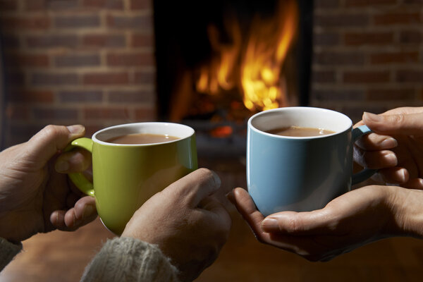 Couple With Hot Drink Relaxing By Fire